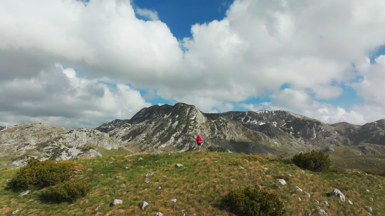 Back of woman in front of majestic Montenegro mountains; drone reveal