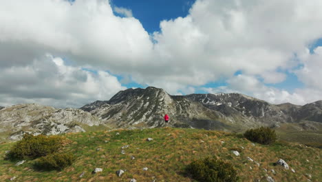back of woman in front of majestic montenegro mountains; drone reveal