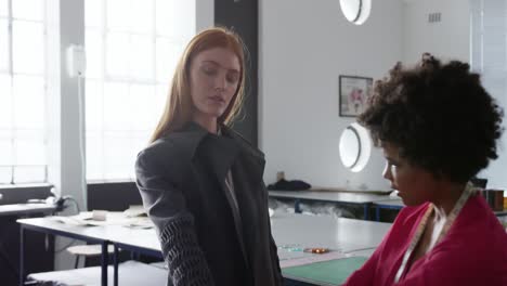 mixed race woman dressing caucasian woman in fashion office