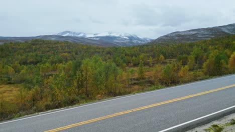 aerial over a deserted main road and towards the forested hills near breheimen, norway