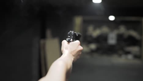 person is doing shooting practice at the firing range, using a gun while taking fire on to aim target