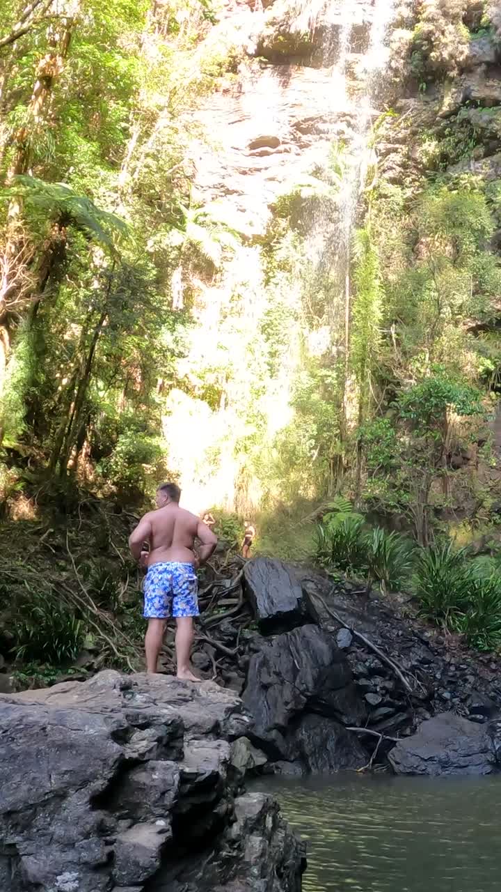 individuo de pie junto a una serena cascada del bosque