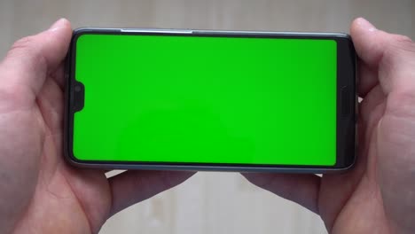 A-person-holding-a-phone-with-a-greenscreen