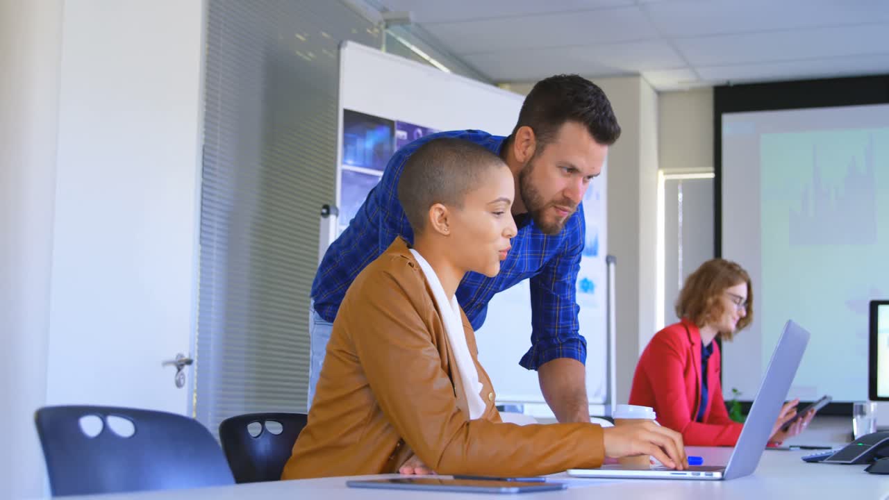 Side view of young caucasian business colleagues discussing over laptop in modern office 4k