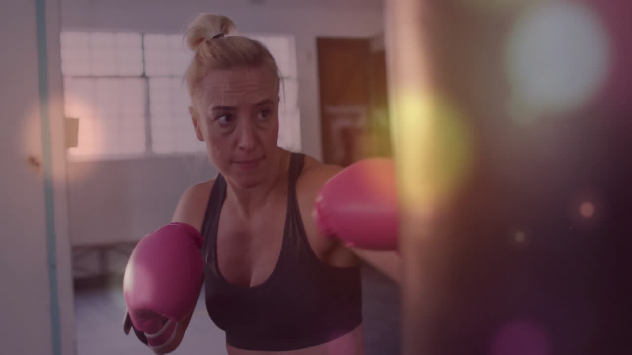 Mulher treinando boxe com luvas rosas sobre animação de luzes bokeh