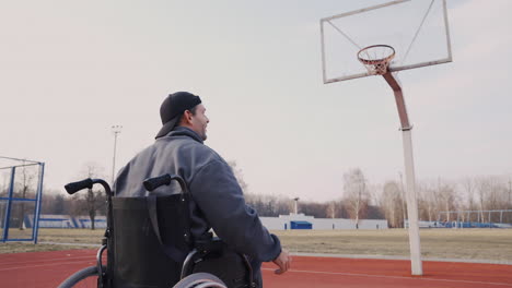 rear view of young disabled man playing to basketball with his friend