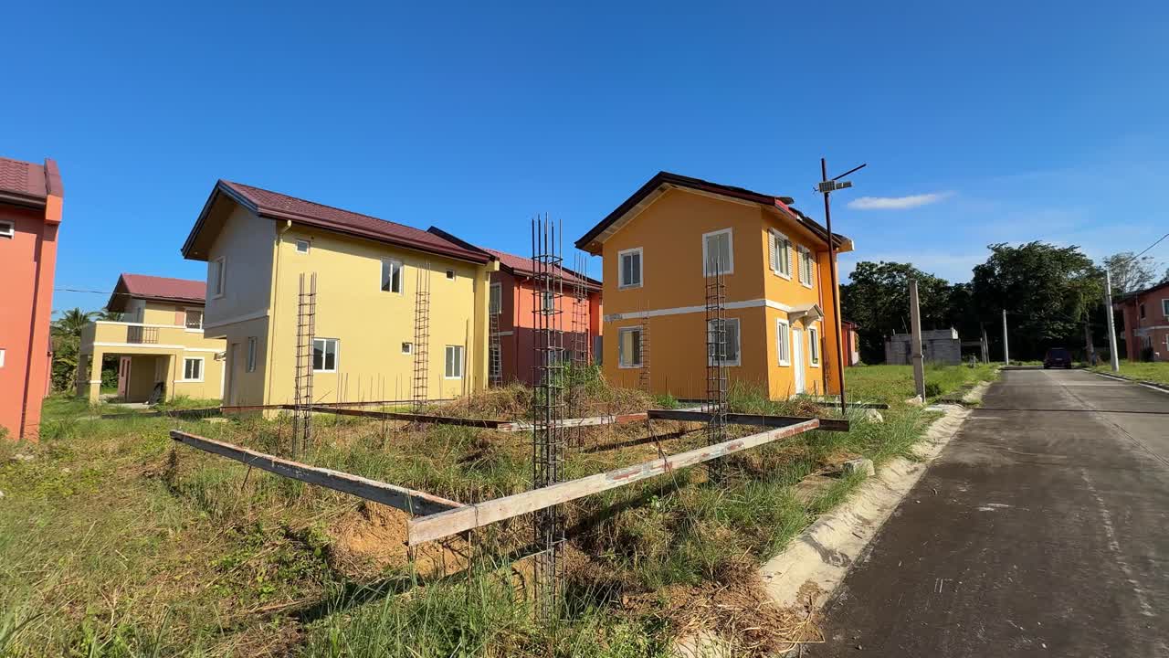 Maatason näkymä, joka näyttää meneillään olevan talonrakennuksen puhtaiden, valmiiden kotien vieressä hyvin kehittyneessä kylässä Camella Homes Alfonso Cavitessa Filippiineillä.