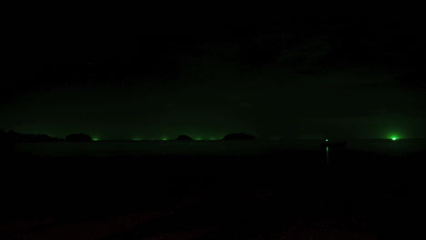 Time-lapse-by-night-during-a-thunderstorm-with-lightning-on-a-Thailand-beach-in-Ko-Chang-island,-the-green-lights-of-fishing-boats-in-the-distance-are-visible