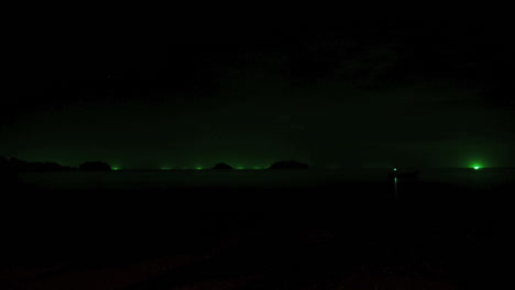 time lapse by night during a thunderstorm with lightning on a thailand beach in ko chang island, the green lights of fishing boats in the distance are visible