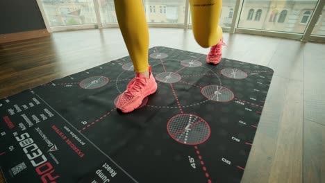 a beautiful girl is training on a special mat with numbers