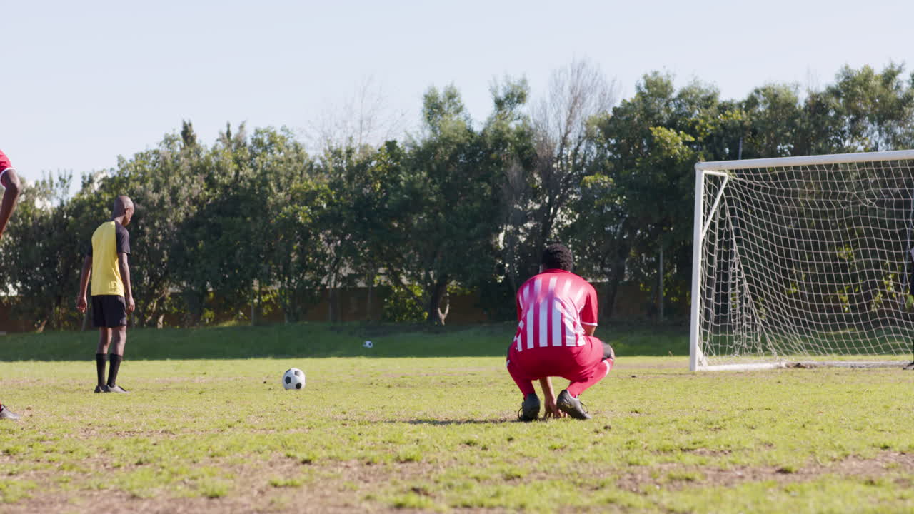Playing soccer, two male players in red uniforms preparing for penalty kick