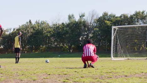 playing soccer, two male players in red uniforms preparing for penalty kick