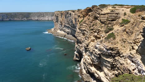 scenic portuguese coastline on atlantic ocean, ridged cliffs in sagres, algarve region, tilt down