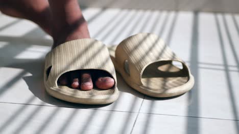 person wearing light beige sandals on a tiled floor