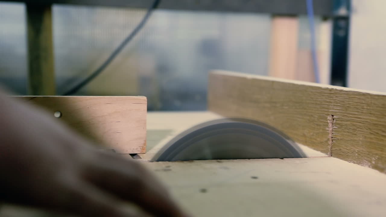 Cutting Wood In Carpenter Workshop With Table Circular Saw. Circular table saw cutting wood in carpenter workshop