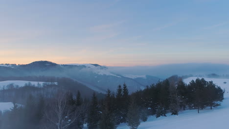 Sobre-Las-Nubes,-Frente-Al-Bosque-Nevado,-Los-Picos-De-Las-Montañas-Y-Los-Colores-Del-Atardecer