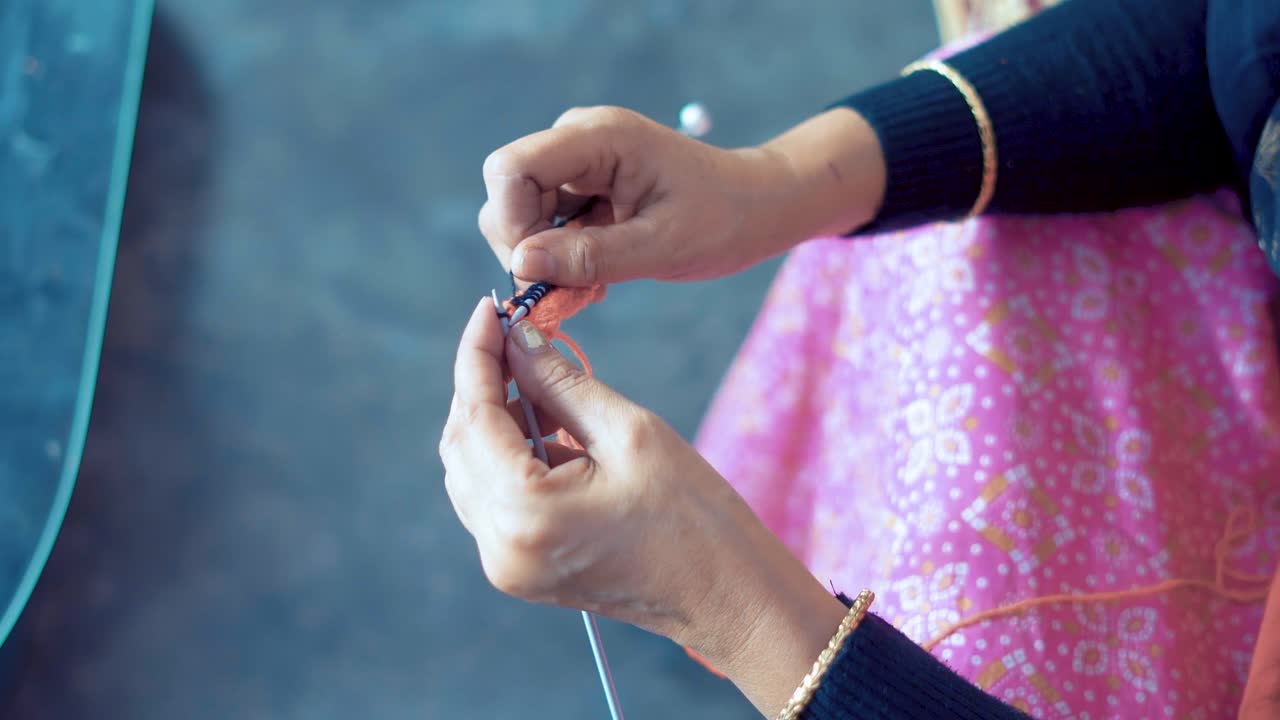 여성이 뜨개질 작업을 하고 손으로 는 작업을 하고 있습니다.