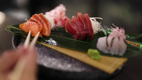 person picking up sushi pieces from a platter
