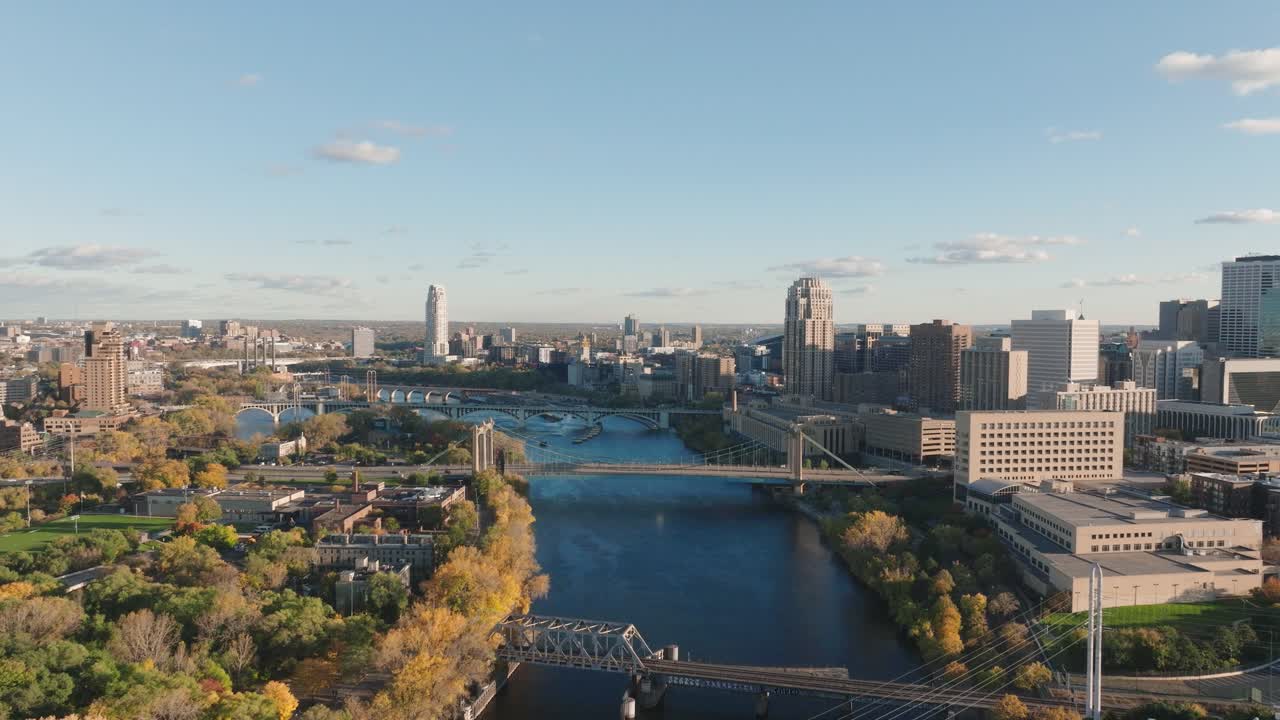 Volo cinematografico con drone sopra l'Hennepin Avenue Bridge e il fiume Mississippi durante l'ora d'oro autunnale, che mostra lo skyline di Minneapolis, MN
