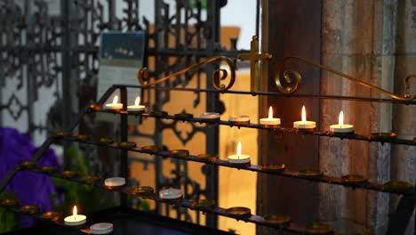 Several-small-lit-wax-candles-flickering-in-St-Davids-Cathedral,-Wales