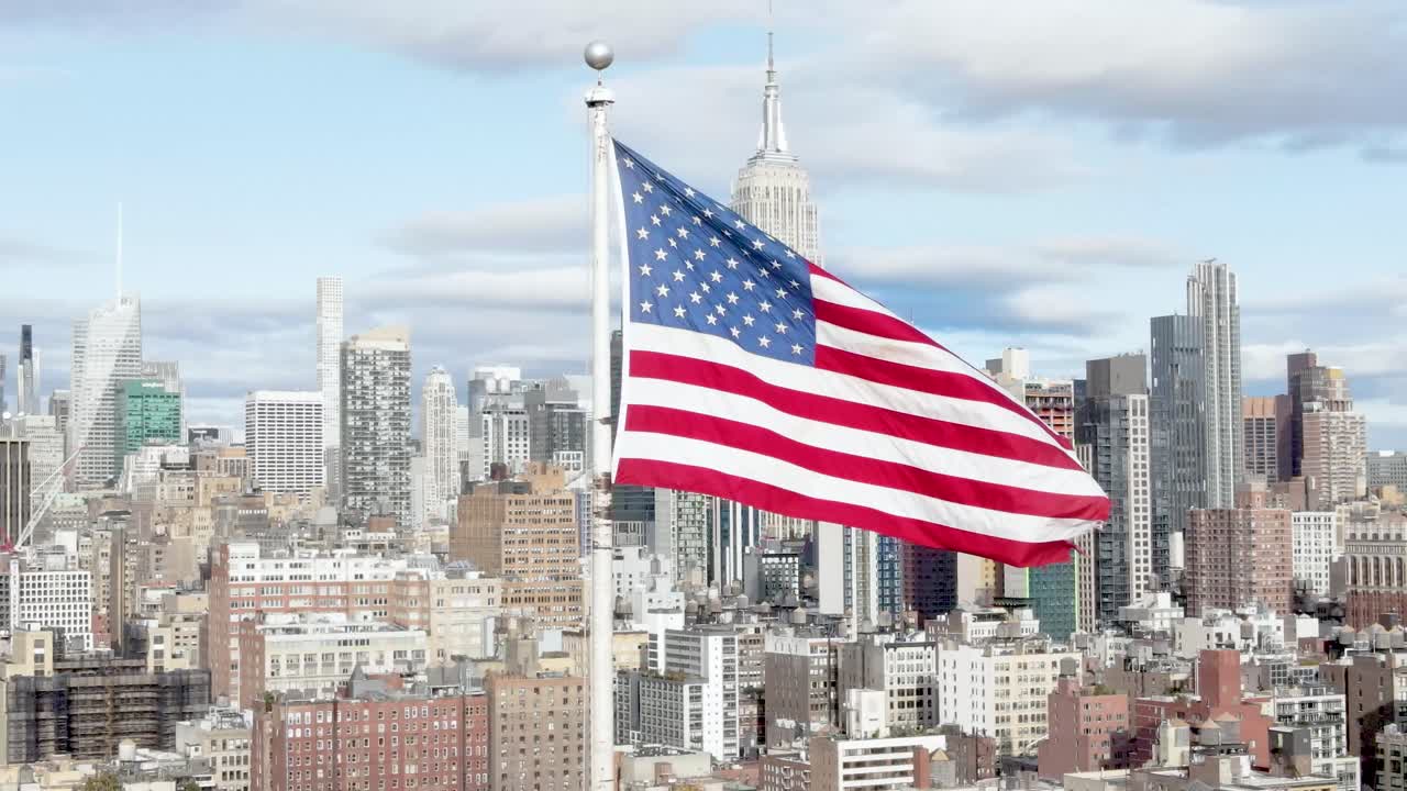 rodaje cinematográfico aéreo de la bandera de los ee.uu. ondeando en el viento con el empire state building en el fondo