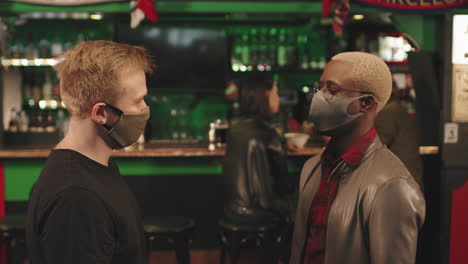 men in masks greeting each other at bar