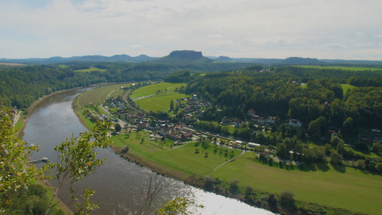 View from Elbsandsteingebirge Sachsen Elbe sandstone formations rising above dense Mountains, under a blue sky with scattered clouds, showcasing the region’s natural beauty and rugged Terrain
