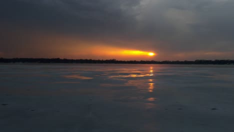 time lapse of sun setting on the horizon on a cloudy winter afternoon over a frozen lake