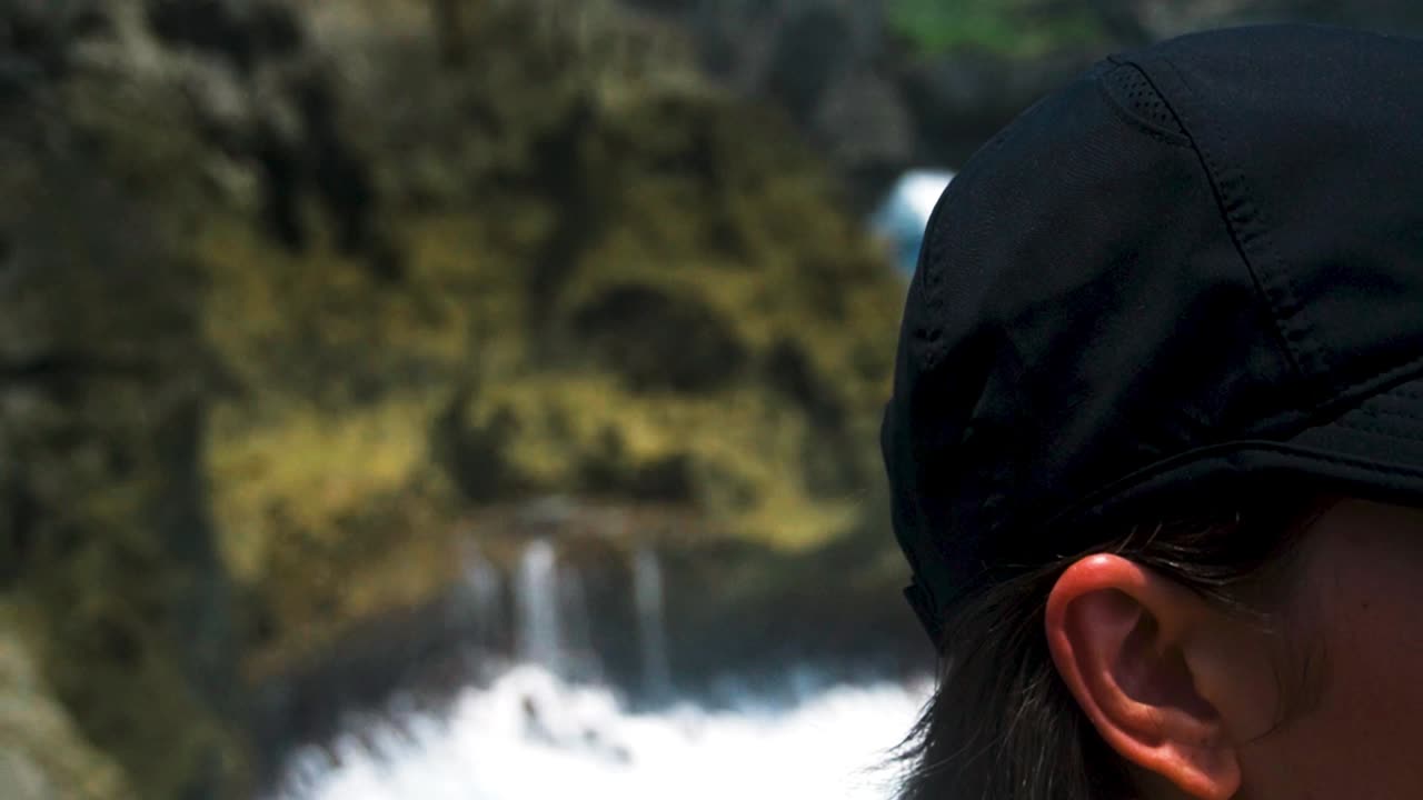 랙 포커스는 부러진 해변 발리의 바위 바다 절벽에서 배수되는 물을 보여줍니다.