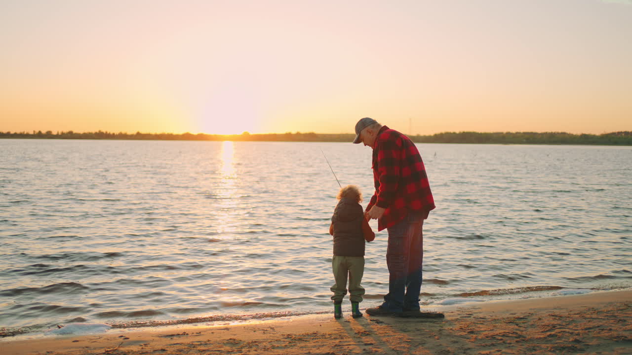 little boy is spending time with grandfather in fishing old man is giving fishing-rod to child