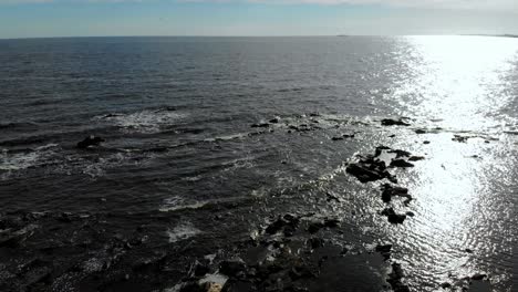 aerial view of stones in the sea with waves crashing on the pier, montevideo, uruguay