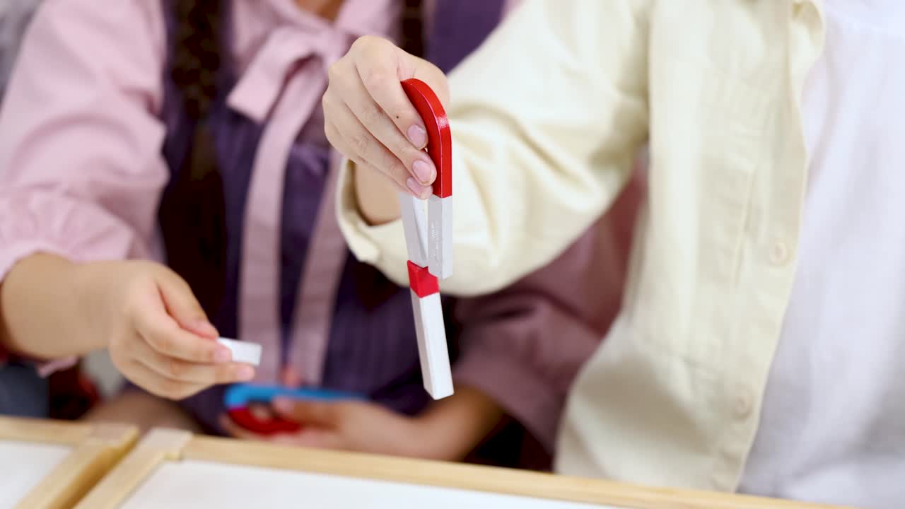 Close up tangan siswa yang sedang melakukan eksperimen sains menggunakan magnet batang merah