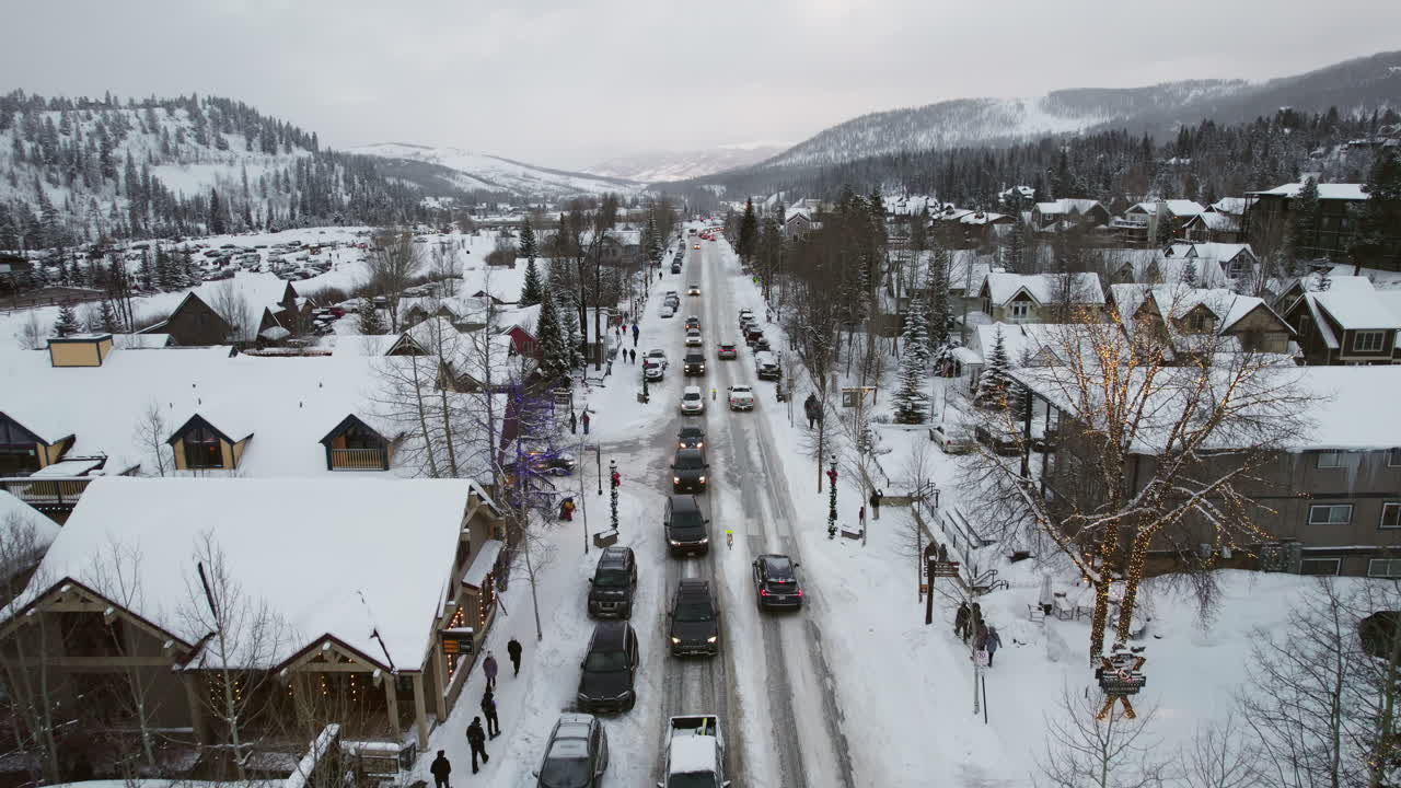 An aerial of a peaceful and beautiful snow-covered Breckenridge, as cars carrying skis and snowboards drive into the popular Colorado mountain town for a ski vacation at the world famous resort.