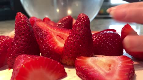hand slicing fresh red strawberries on a cutting board with a knife. close-up. 4k