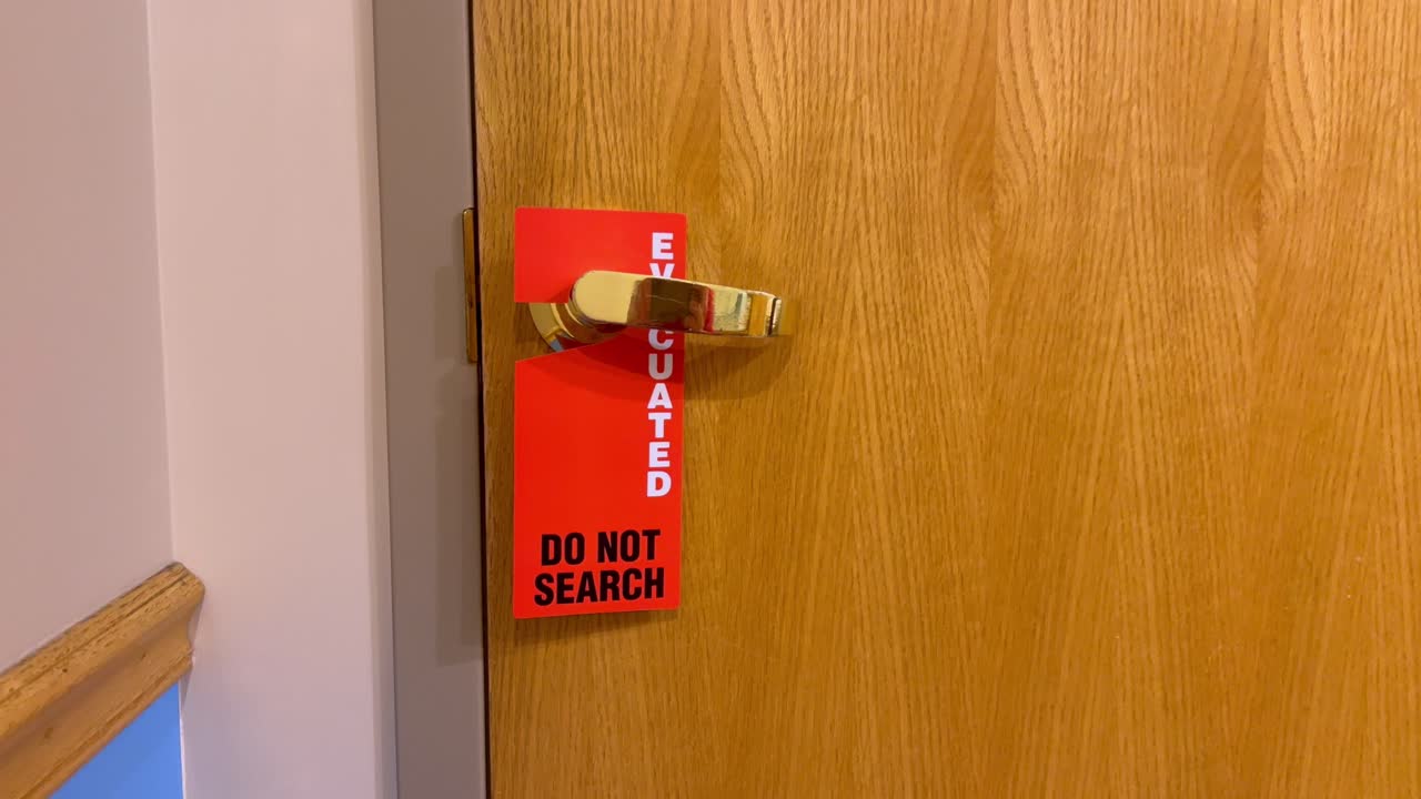Evacuated Do Not Search bright orange and red sign on Doctor’s office hospital wood door with gold handle - Shot on iPhone 13 Pro Max - 4k 60fps Real Time.