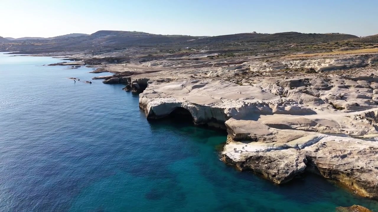 La costa di Sarakiniko mostra scogliere vulcaniche bianche, piattaforme rocciose erose e una grotta marina color turchese a Milo, Egeo meridionale, Grecia, Europa, ripresa aerea