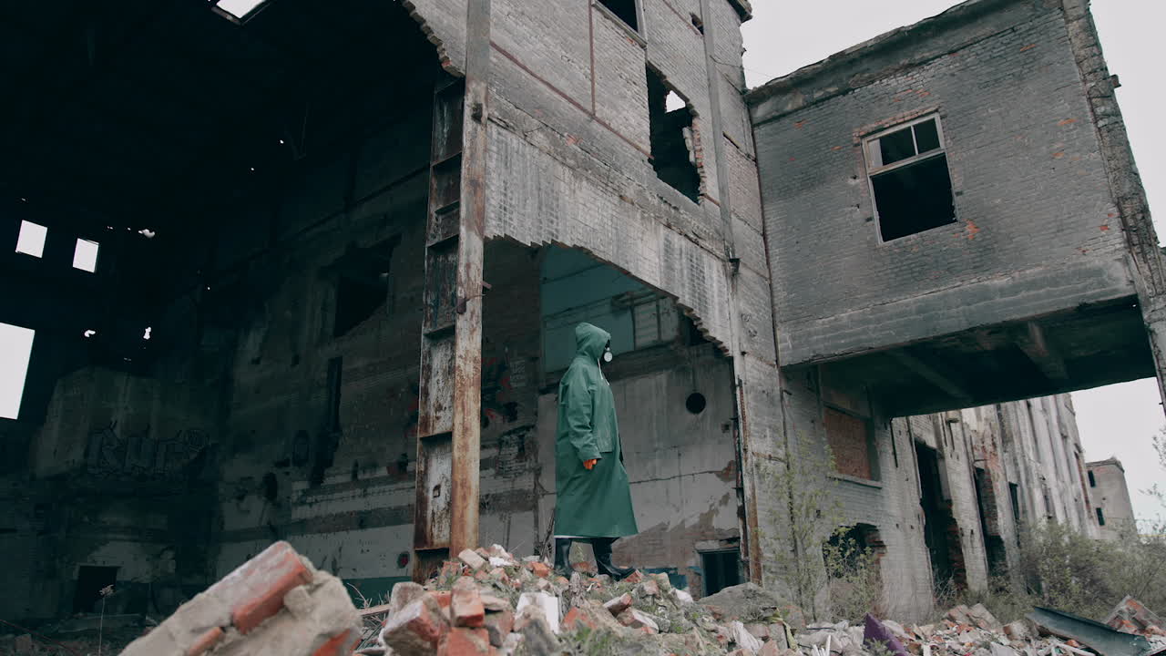 Survivor in safety suit in ruined place. Man in gas mask and protective wearing standing alone in abandoned place. Post-apocalyptic concept.