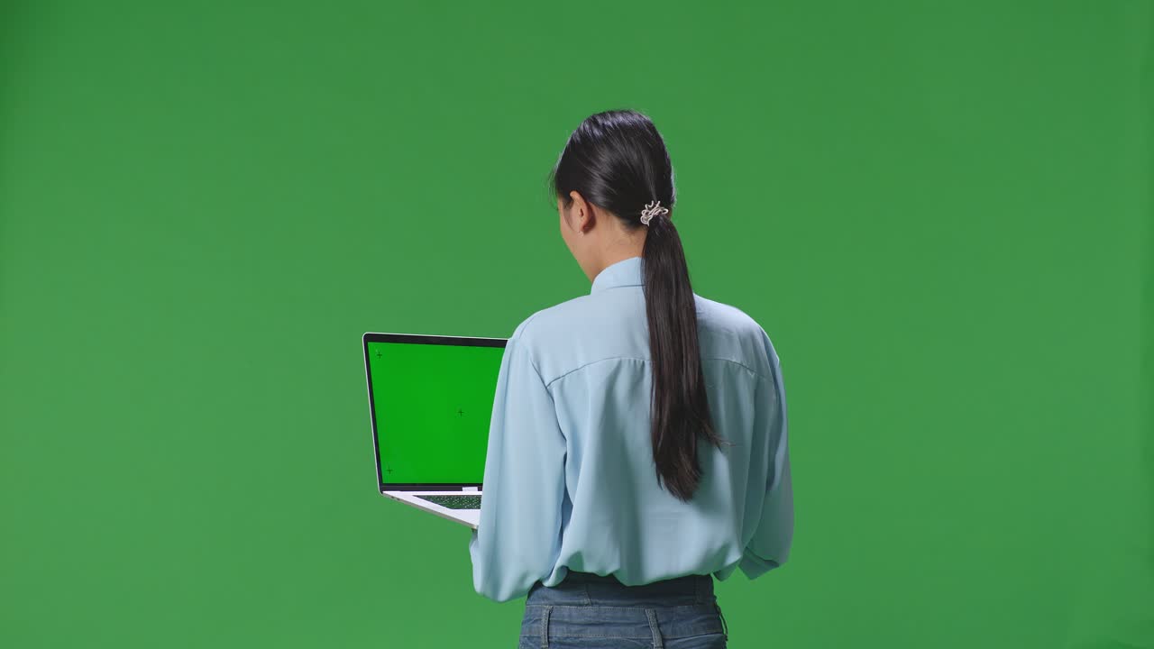 vista trasera de una mujer de negocios asiática usando una computadora portátil con una pantalla verde simulada en el fondo de la pantalla verde en el estudio