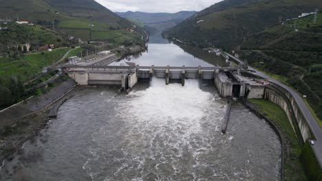 regua dam spillway in action on douro river, portugal - aerial