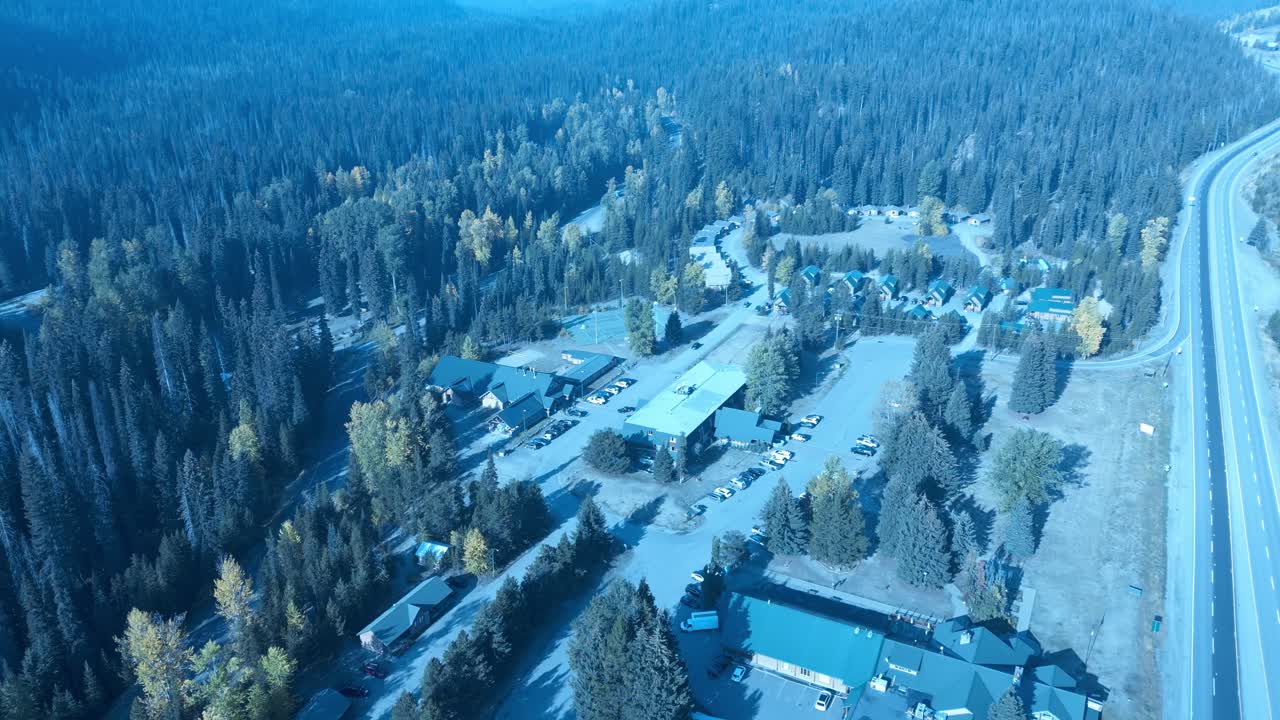 manning park pájaros aéreos vista superior sobrevuelo con vistas al hotel presort, piscina cubierta, canchas de tenis al aire libre, filas de chalés separados por árboles en los verdes del valle de la montaña que cambian de color 3-3