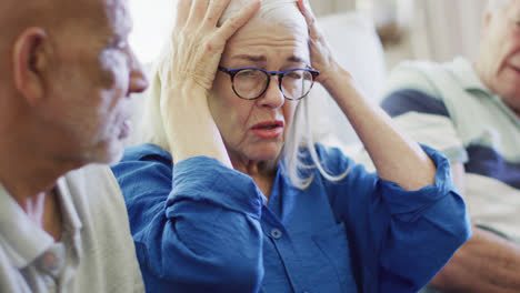 Dstressed senior caucasian woman talking to diverse male friends in living room, slow motion