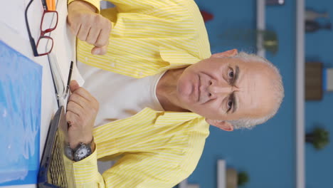 Vertical-video-of-Home-office-worker-old-man-looking-nervously-at-camera.