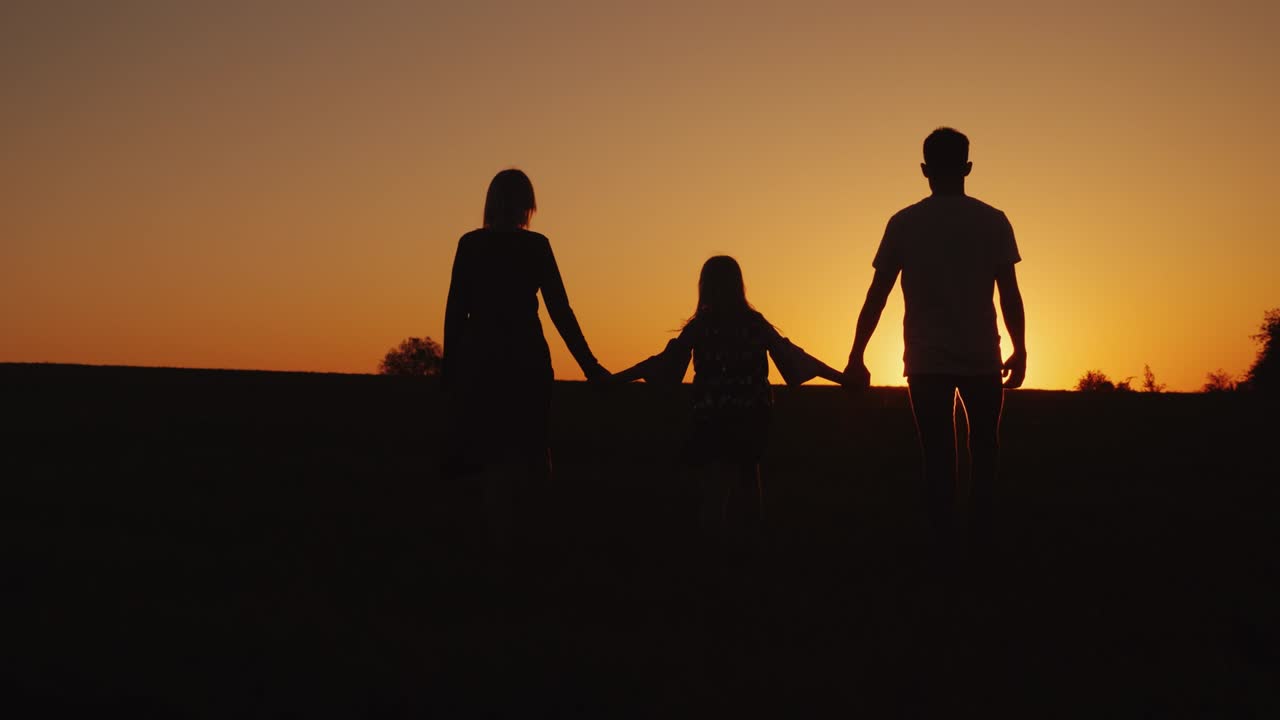A family of three goes forward at sunset