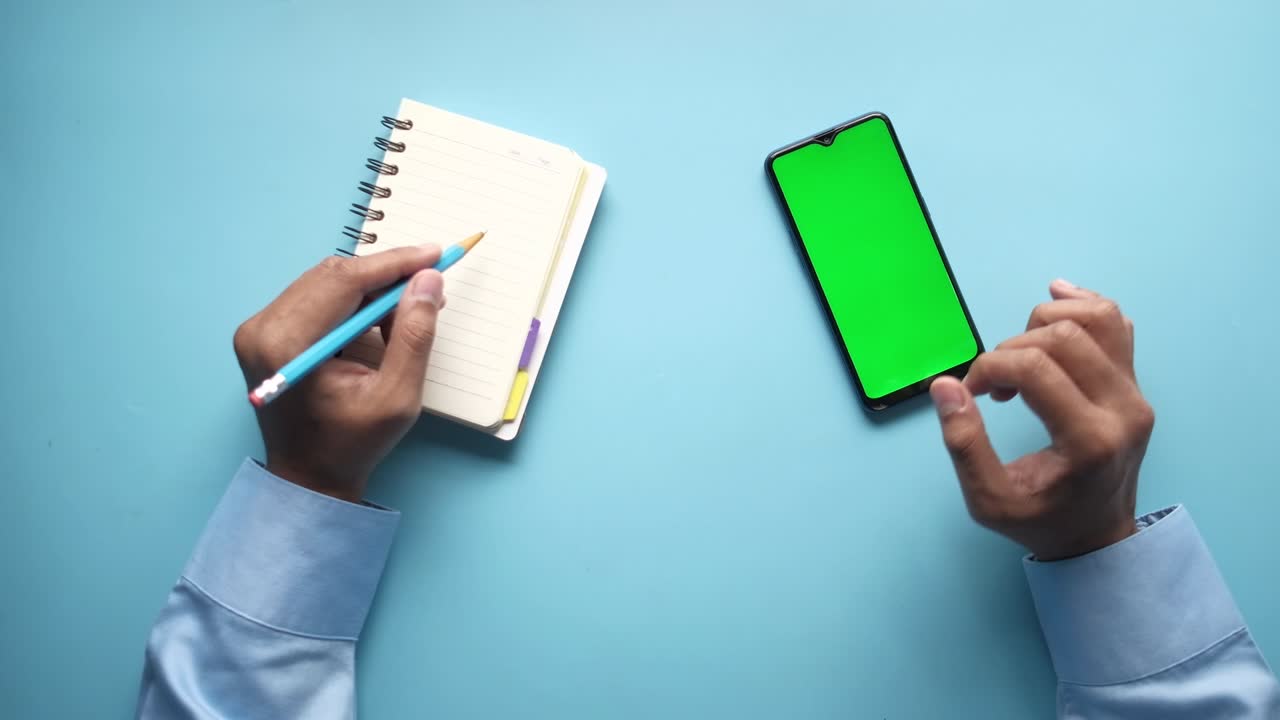 man hand using smart phone and writing on notepad