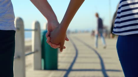 primer plano de una pareja caminando de la mano en el paseo marítimo 4k