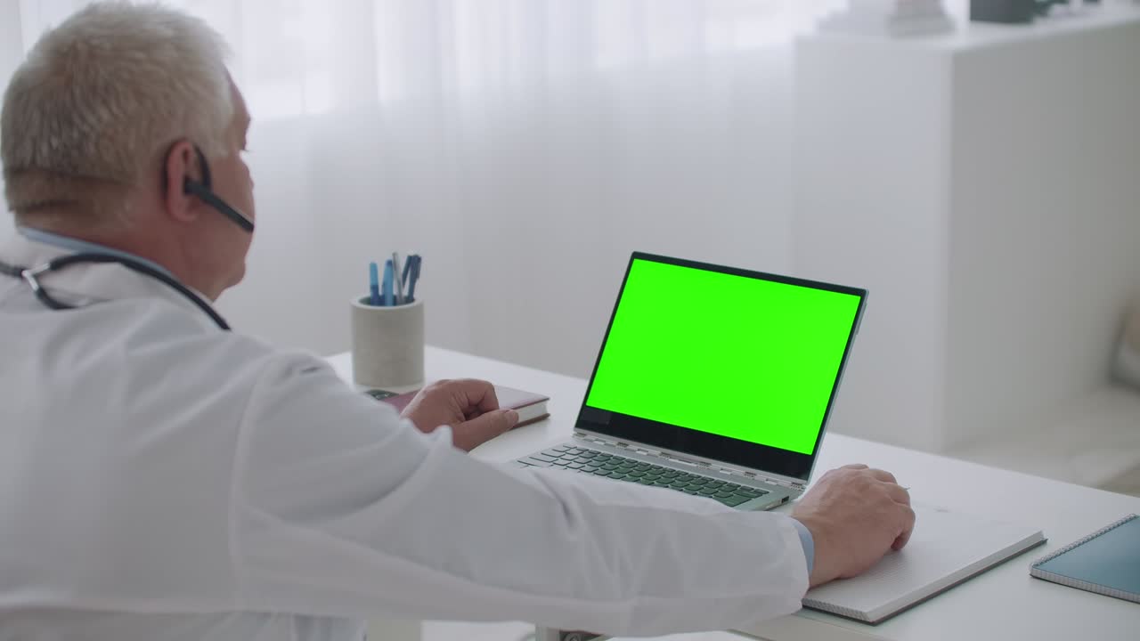 online appointment with therapist, doctor is using laptop with green display for chroma key technology, telemedicine session