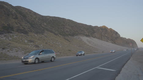 Toma-Panorámica-De-Automóviles-Y-Camiones-Conduciendo-Por-La-Autopista-De-La-Costa-Pacífica-Ubicada-En-El-Sur-De-California