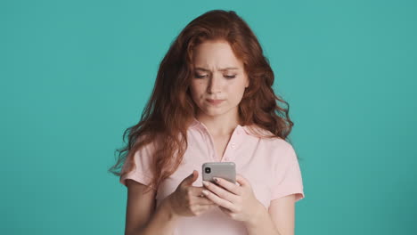 Redheaded girl in front of camera on turquoise background.