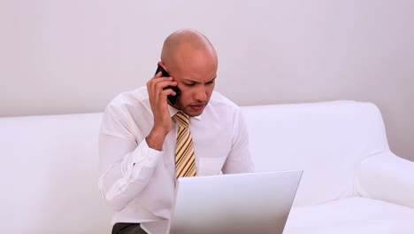 Happy-businessman-sitting-on-couch-working