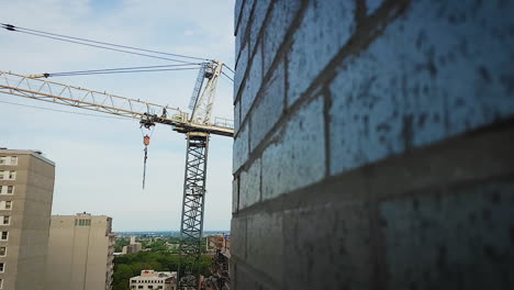 a large industrial crane peeks out from behind a brick wall